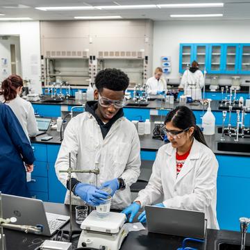 Two students working with equipment in a lab