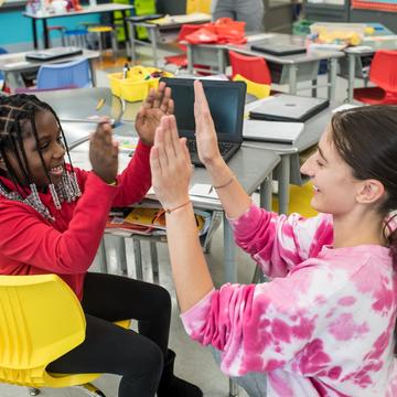 Student giving a high five to an elementary student in a classroom
