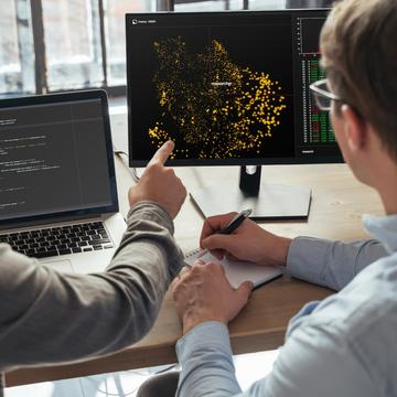 Two people pointing at data on a computer