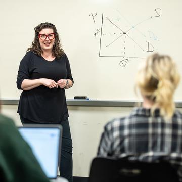 Teacher speaking to a classroom in front of a whiteboard