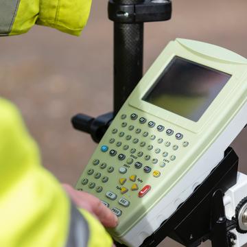 Person pressing a button on a handheld computerized geographic information system device