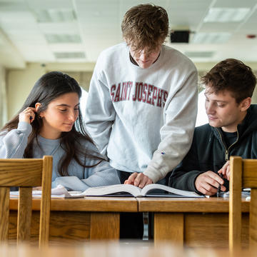 Three students studying a textbook in the library
