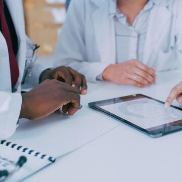 Zoomed in image of two doctors pointing to a tablet with data