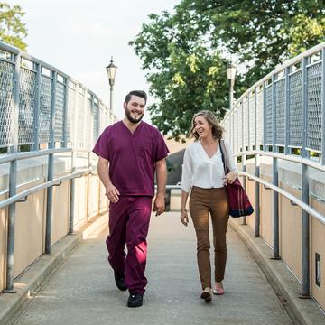 Student walking in scrubs with a student in regular clothes on Saint Joseph's campus