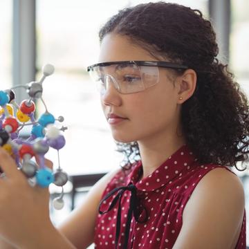 Student wearing goggles in a lab studying a molecule structure 