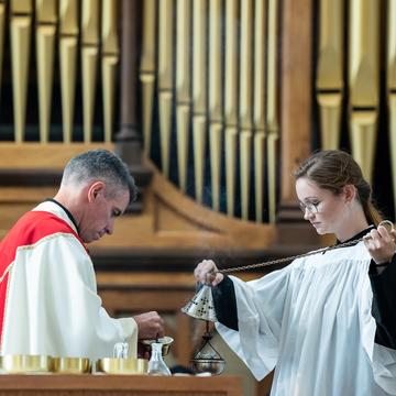 Student leading service in chapel with a priest