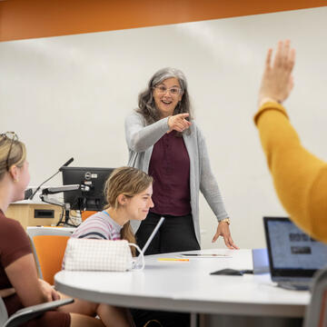 Professor pointing to a student with a raised hand in a classroom