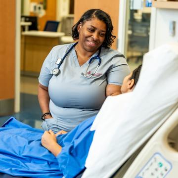 Nursing student speaking with a patient at the patient's bedside