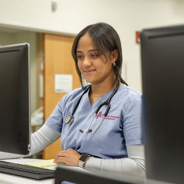 Saint Joseph's female nursing student on computer with stethoscope around her neck