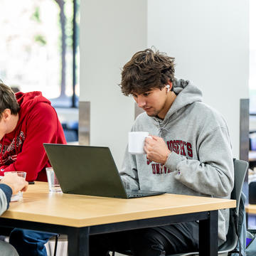 Saint Joseph's University students sitting in dining hall with laptop