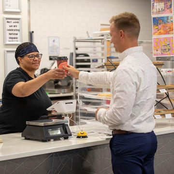 Female barista handing male customer a cup of coffee