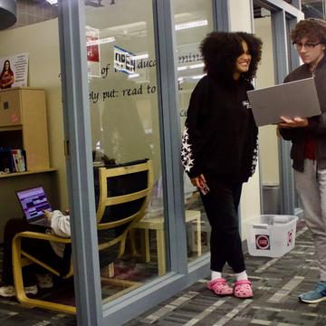 Two students conversing in front of Writing Center PLC location