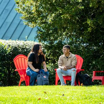 Two Saint Joseph's students sitting on red chairs outside of Foley Center