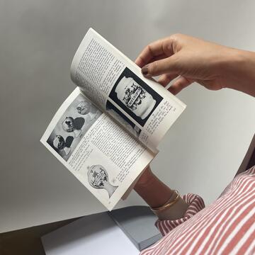 Book pages showing black and white apothecary jars, held open in the artist's hands