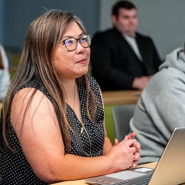 female student sitting at desk in class with hands crossed