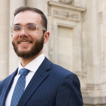 Man wearing navy suit standing in front of a building