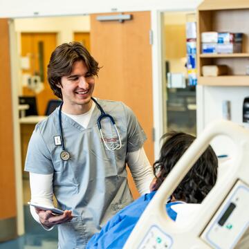 Male nurse assisting female patient on a hospital bed