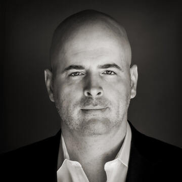 Headshot of Patrick Hughes wearing suit