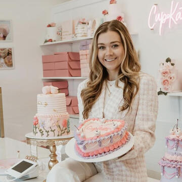 Female business owner inside bakery holding cake