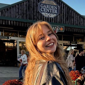 A woman smiling in front of a sign that reads Garden Center