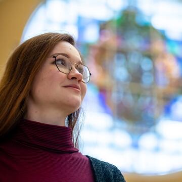 student looking up with stained glass in the background