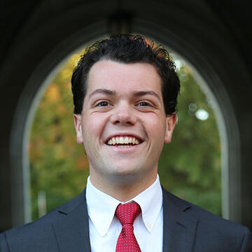 A man smiling at the camera in a suit and red tie