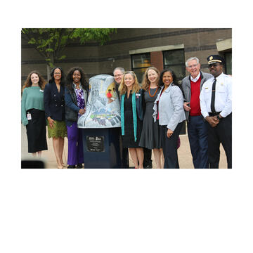 university leaders standing in front of bell sculpture