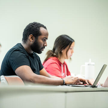 two students in classroom working on their laptops