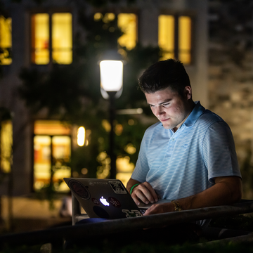 Student on laptop outside Haub School of Business