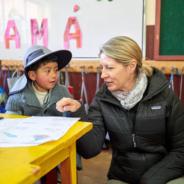 a young boy talking to a woman in a classroom