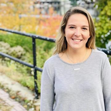 Danielle smiles with a fence and greenery behind her