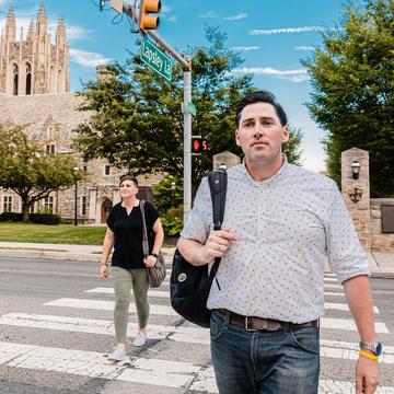 Two students crossing the road at a crosswalk.