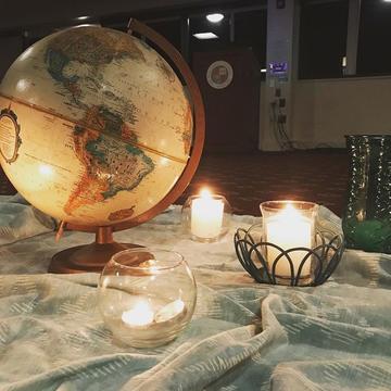A large globe of the Earth sits on a table next to flickering candles