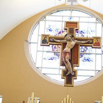A crucifix hanging in front of a stained glass window