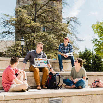 Saint Joseph's University students sitting on the steps in front of the Drexel Library