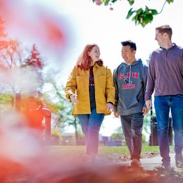 three students walking and talking outside during fall