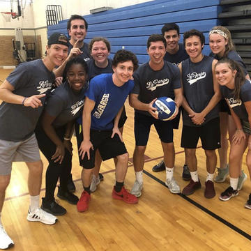a group of students pose with a volleyball on a court