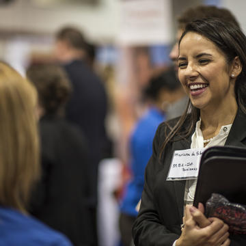 A young student smiles and chats with a potential employer at the Career Fair.