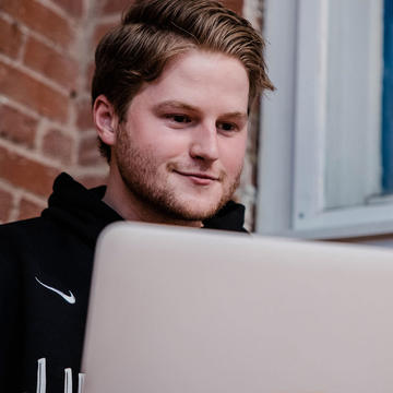 a male online student looking at a computer smiling