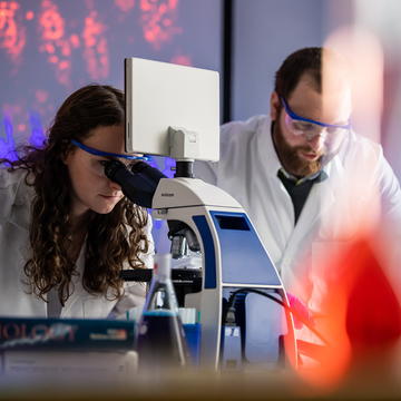 Saint Joseph's University PharmD students in a lab looking at a microscope and lab work.