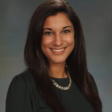 Rachel wears a black dress and a silver necklace in her headshot
