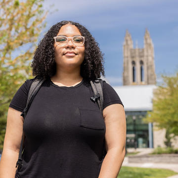 female student walking on saint joseph's campus with barbelin hall behind her