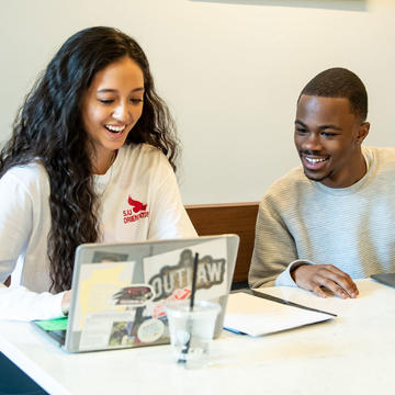 Two students talking in front of a computer