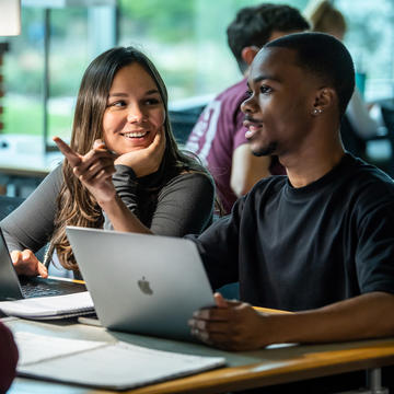Two college students talking to each other in the library Saint Joseph's University