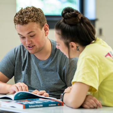 two students talking to each other inside a classroom at saint joseph's university