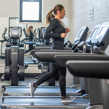 college student running on a treadmill at the gym