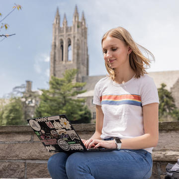 saint joseph's university student on her laptop with barbelin hall behind her
