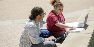 two saint joseph's university students writing outside on campus