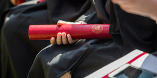 Saint Joseph's graduate holding a diploma during Commencement.