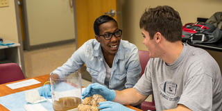 two saint joseph's university students talking to each other in a lab